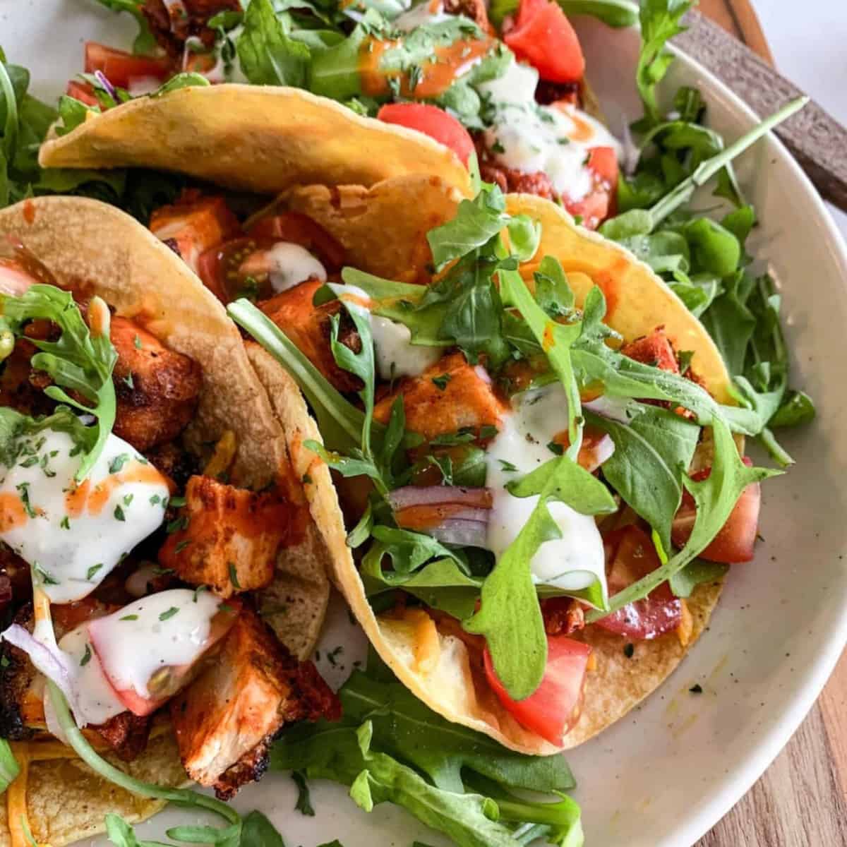 These Buffalo Air Fryer Chicken Tacos are filled with chicken, sweet potatoes, buffalo sauce and arugula. The golden brown sweet potatoes and chicken are made in the air fryer! Then the warm tortillas are warmed up in the air fryer as well! Cooking in the air fryer basket helps make these tacos in record time. They are easy to throw together and make for a perfect taco tuesday! These tacos are spicy and smothered in buffalo sauce. This easy recipe is gluten free, dairy free and are nut free! 