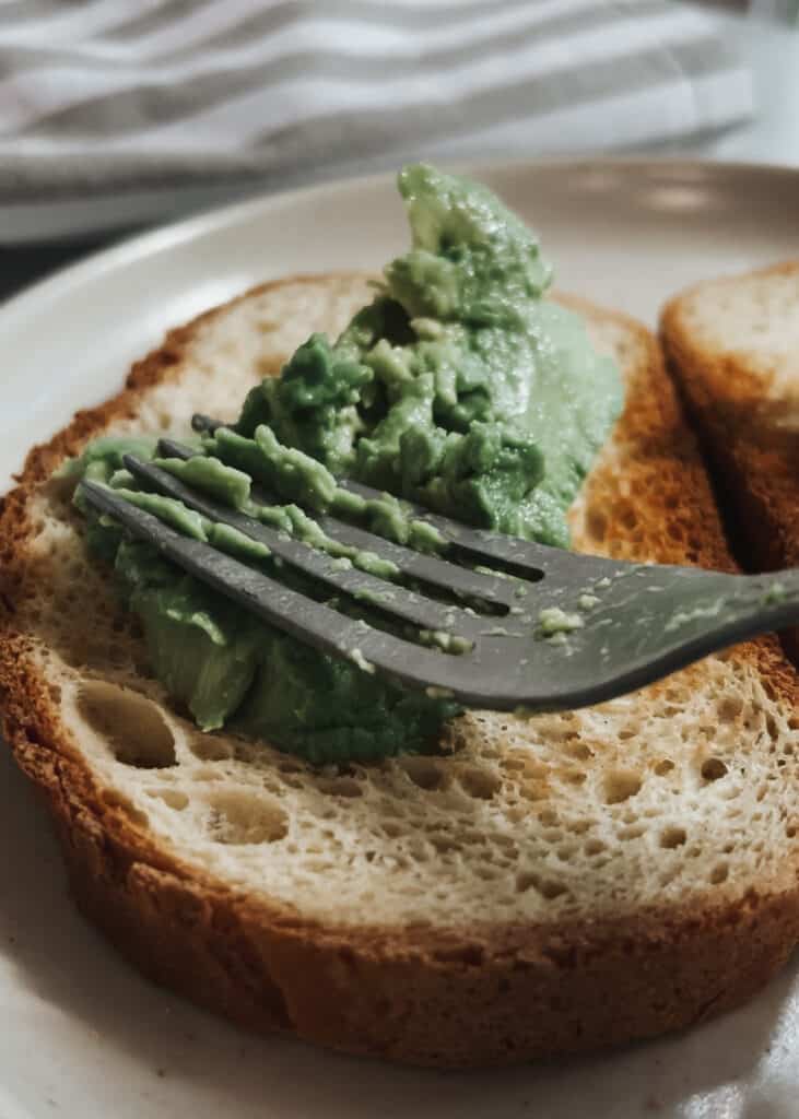 spreading avocado on gluten free bread