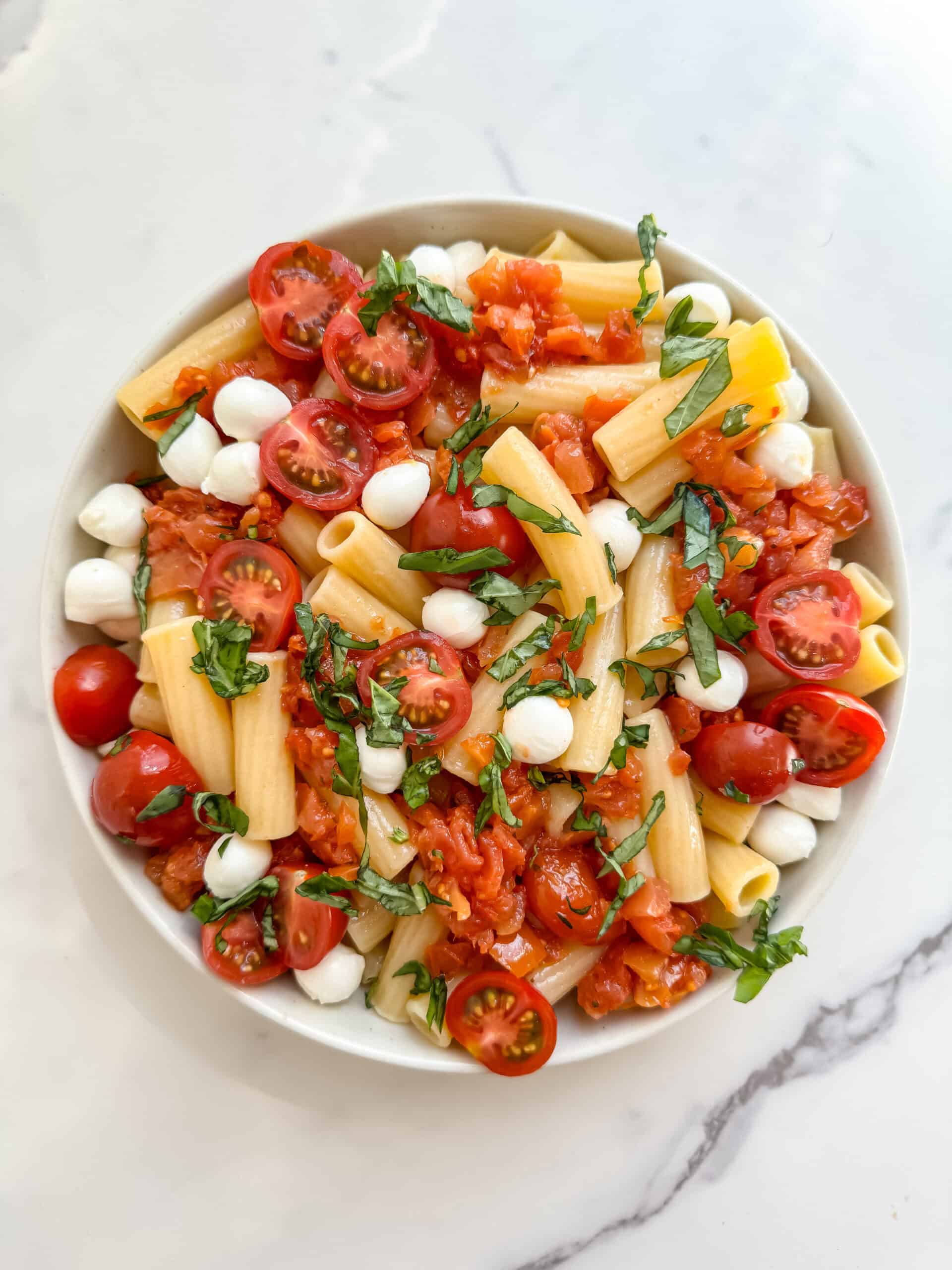 pasta in a bowl with tomatoes, mozzarella and basil